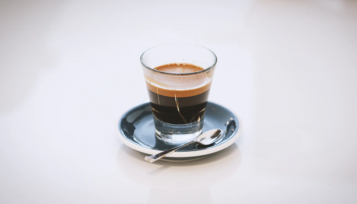 A double espresso in a glass on a blue saucer